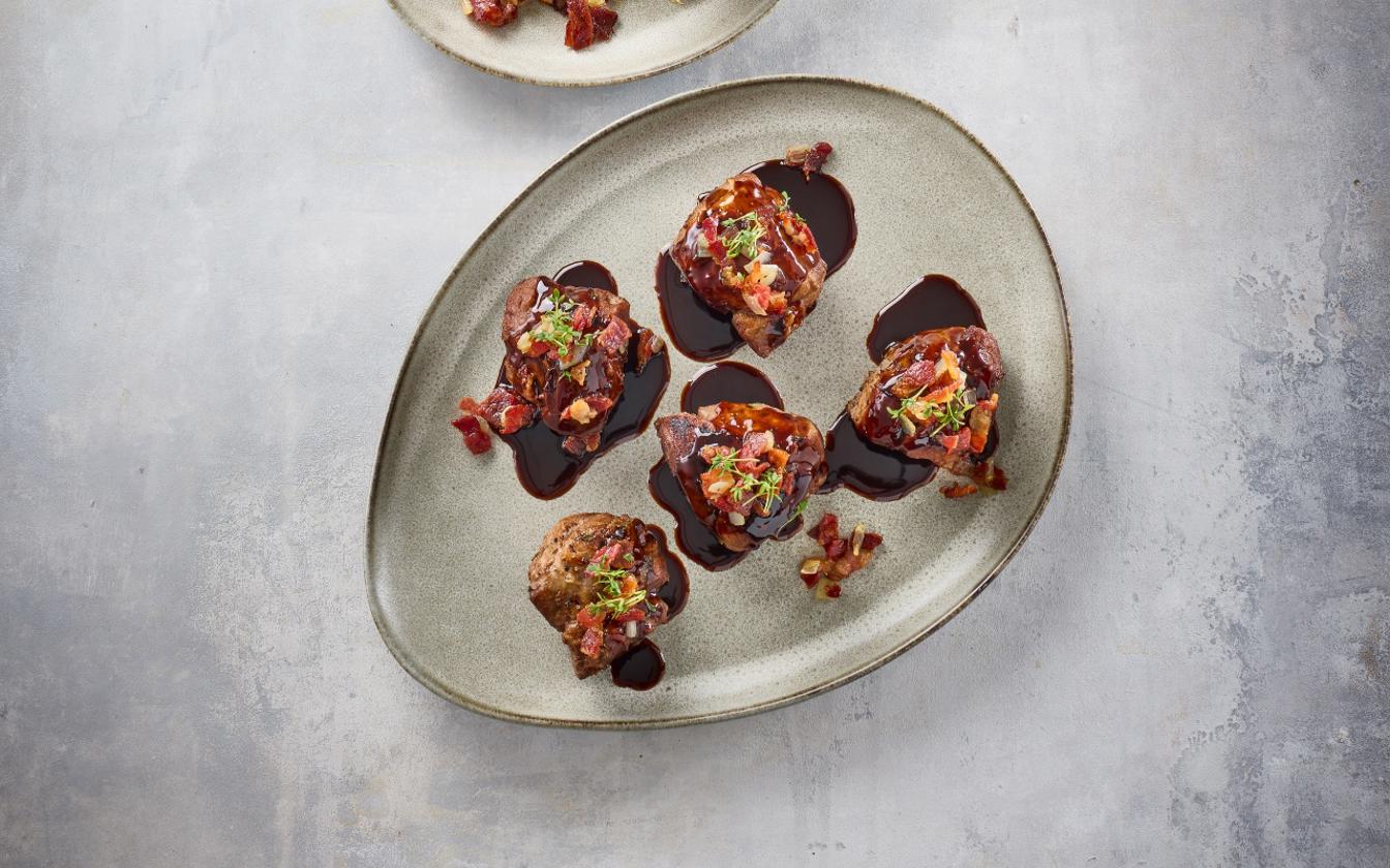 Skankeklumper af gris med rødvinssauce, baconflager og hakkede skalotteløg