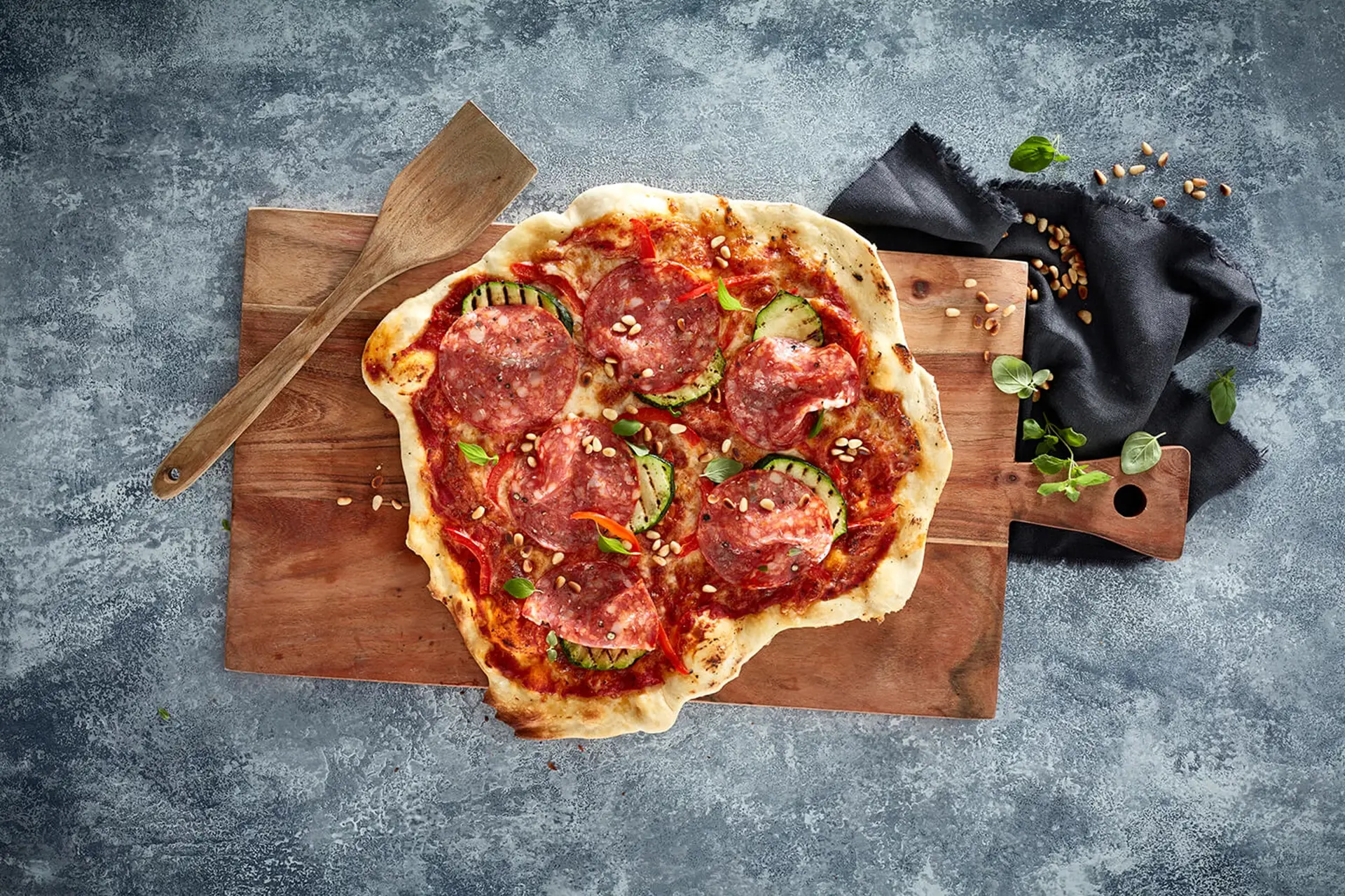 Pizza med italiensksalami, grillad zucchini och rostade pinjenötter